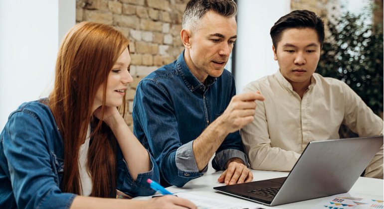 Professionals mapping workflow steps together around a laptop.